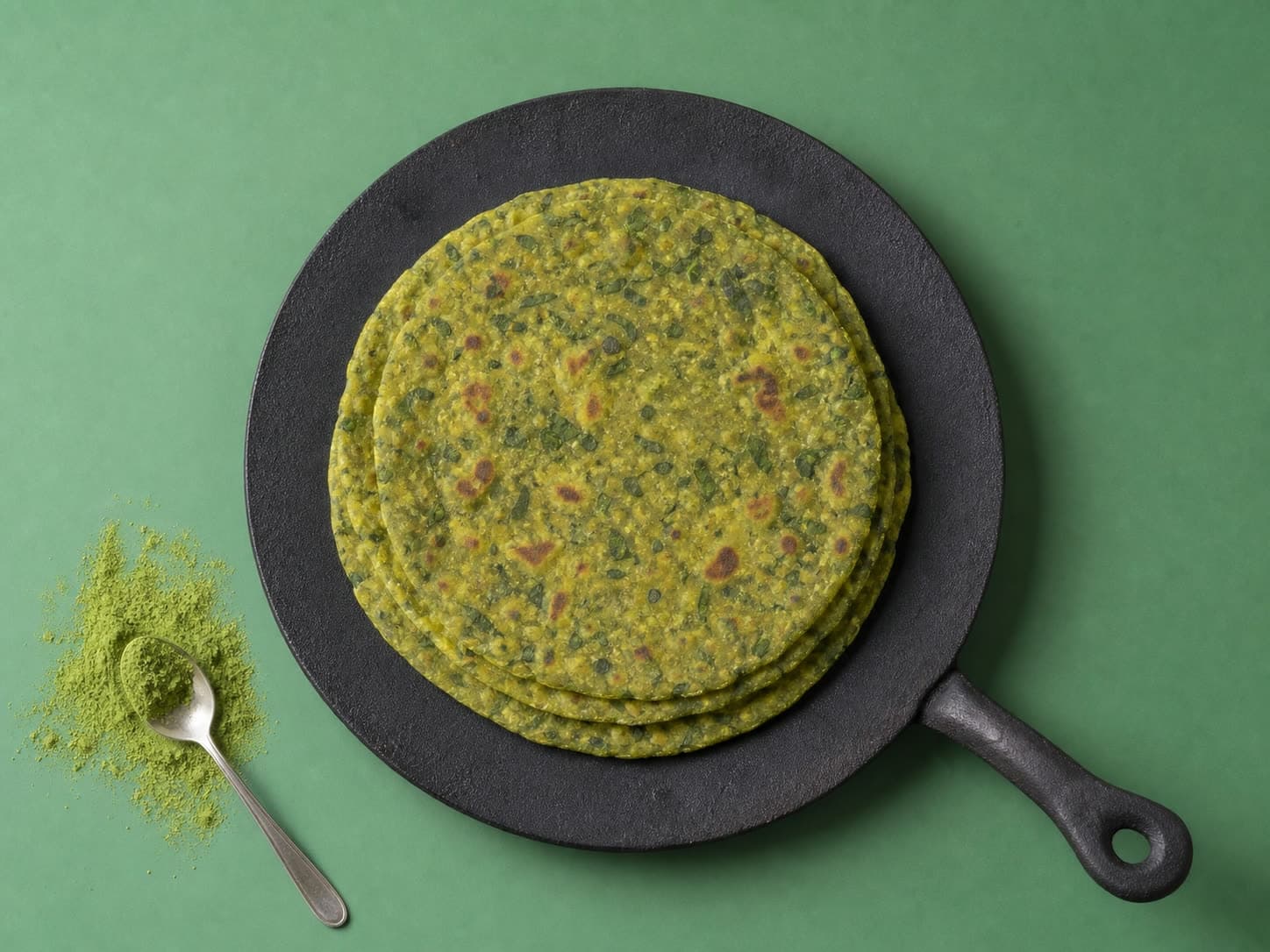A stack of green Moringa Parathas on a tawa